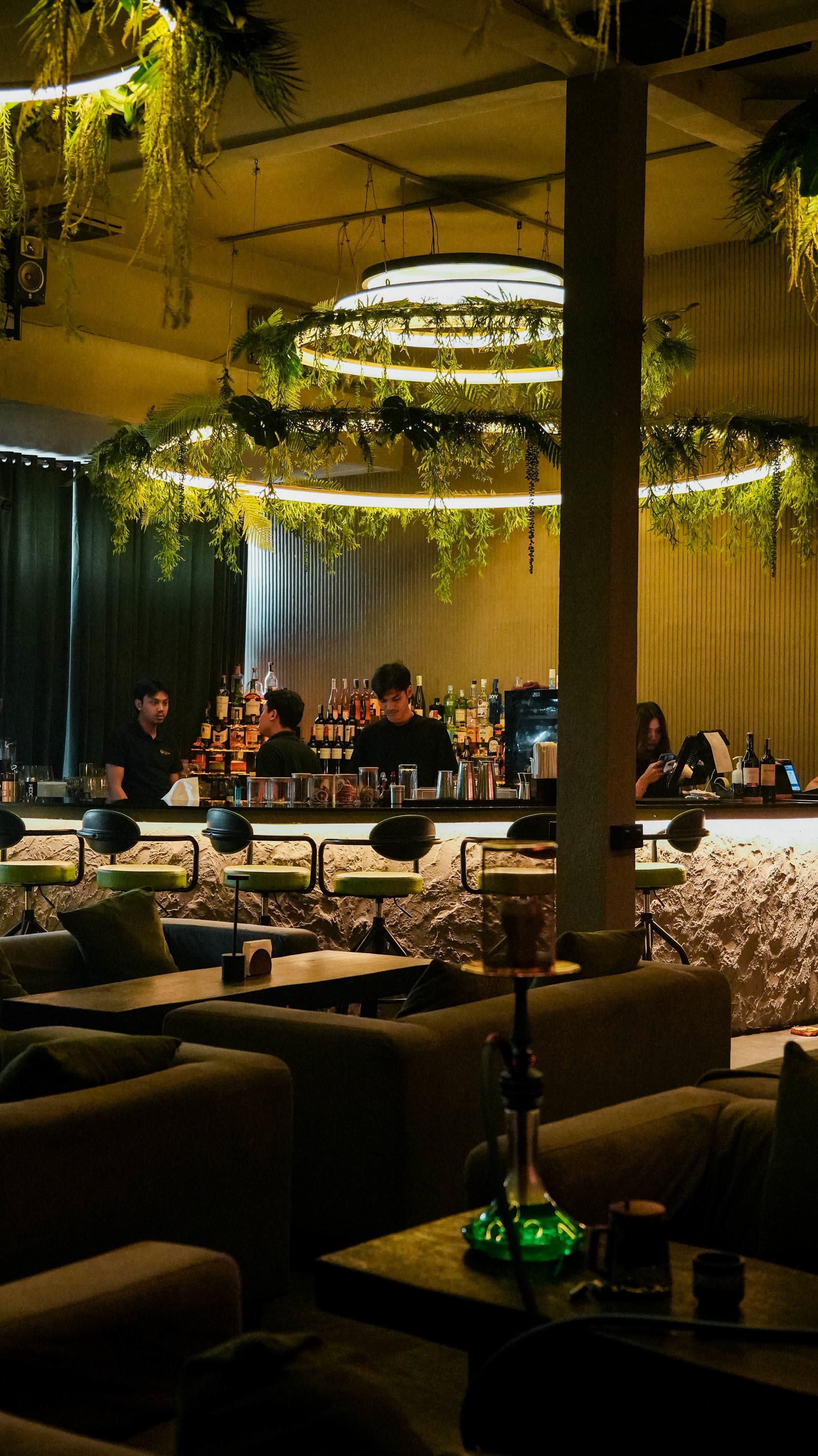 Bar counter, stools and sofas under a ring of light