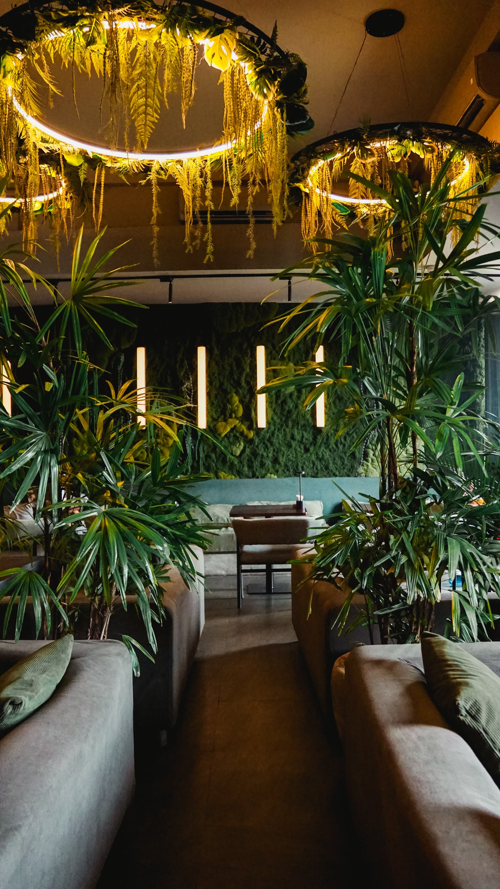 The Moon Lounge dining room with a moss wall, palms and sofas